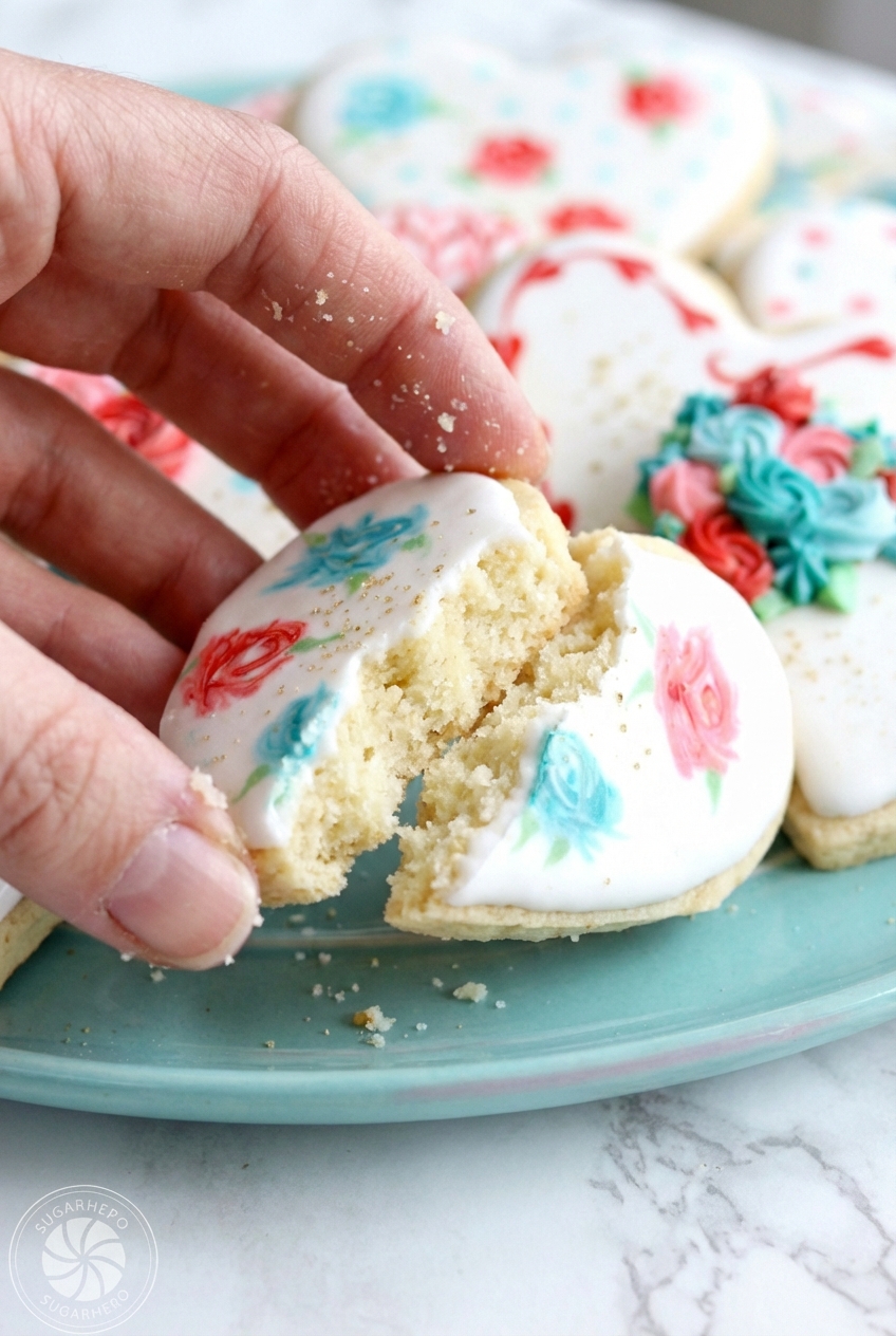 Close-up of heart-shaped valentine sugar cookies showing the smooth flooding technique and speckled cardamom texture.